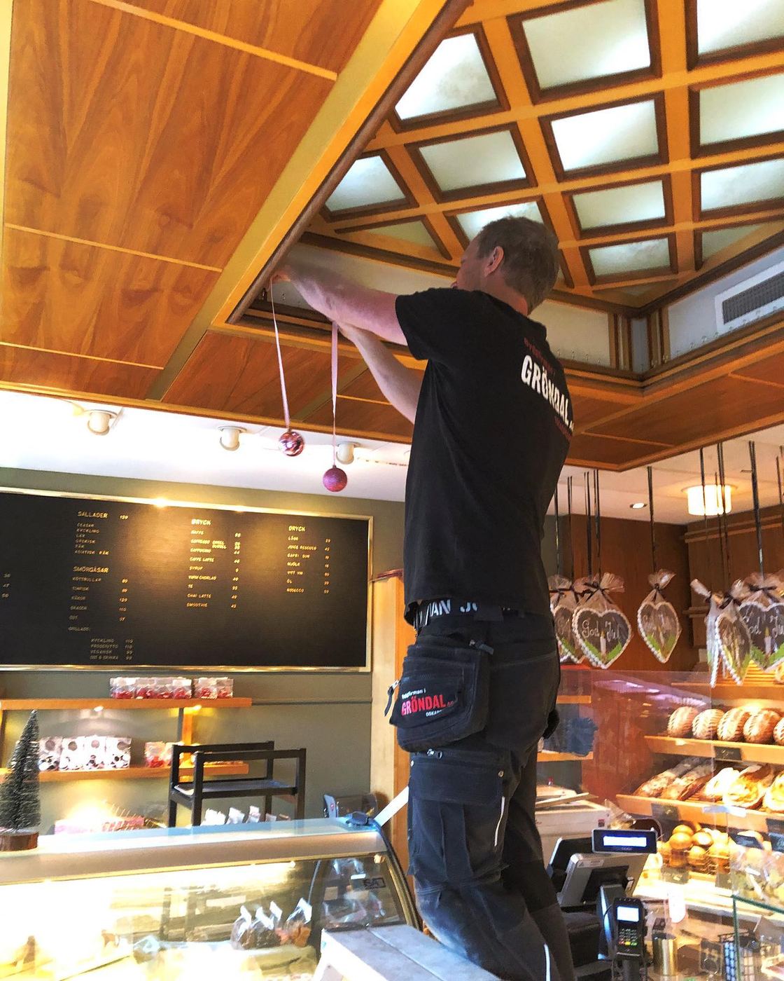 Snickare från Gröndals Bygg hänger upp julpynt i taket på ett konditori i Oskarshamn