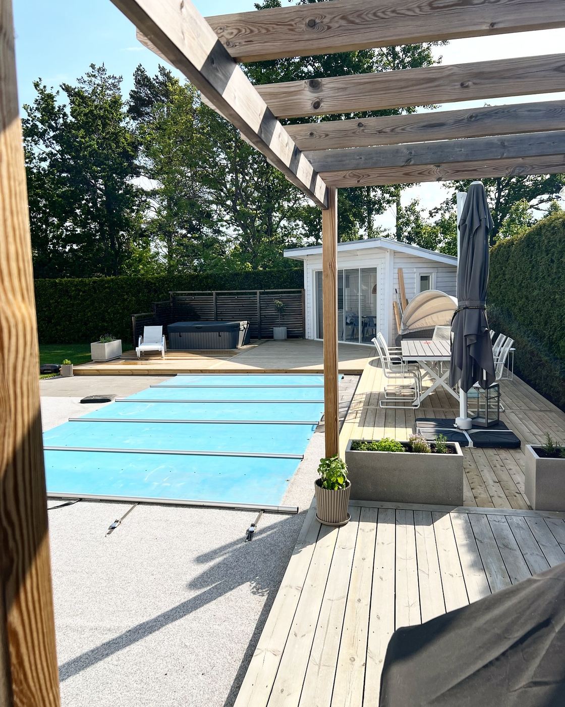 Trädäck och pergola vid pool med uteplats