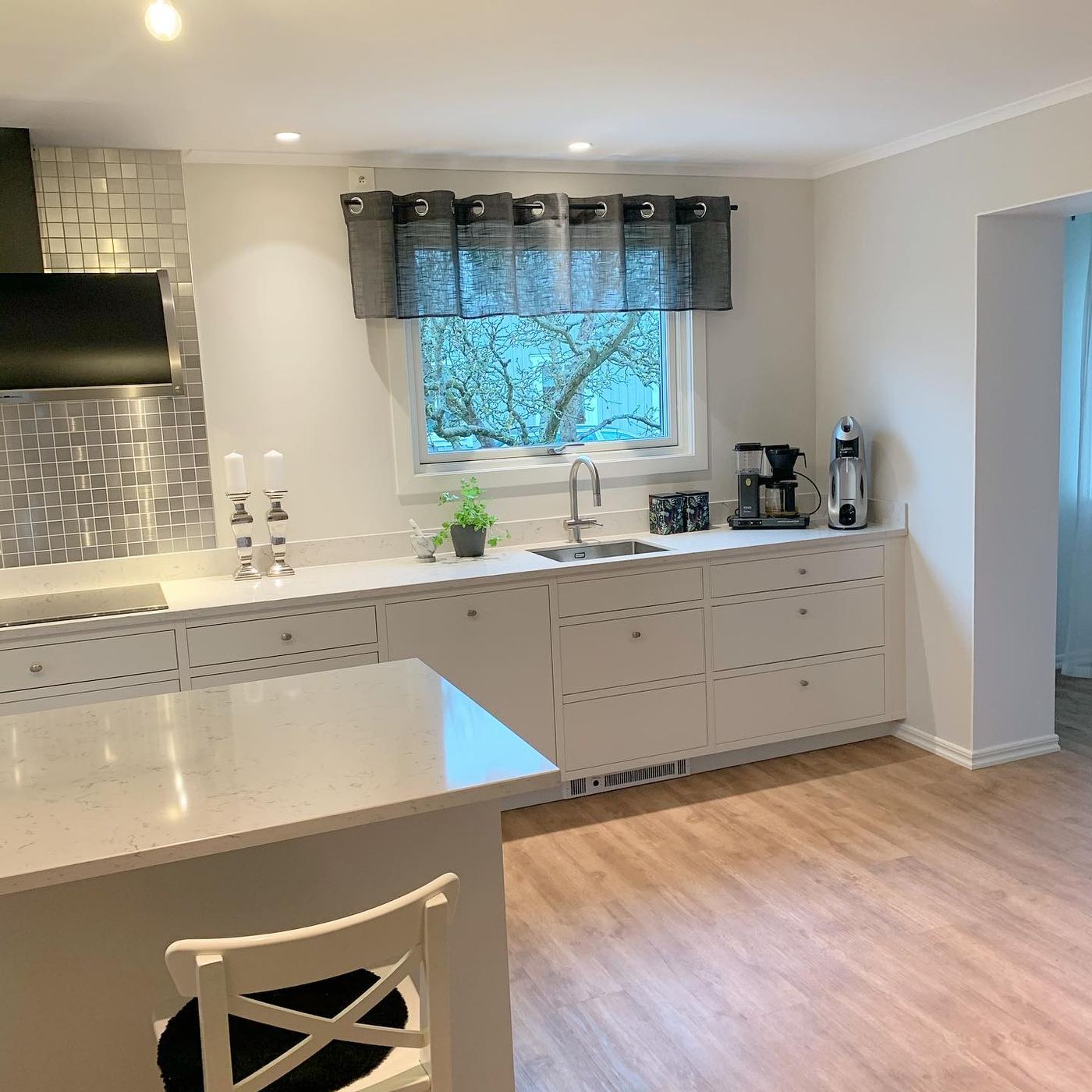 Vitt Sentens-kök med köksö och stenbänkskiva efter köksrenovering i Påskallavik